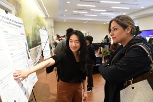 Photo from Women in AI event of a student showing an event attendee their poster presentation.