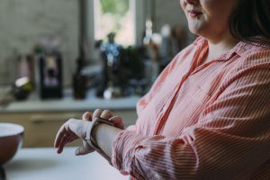 An adult checks their smartwatch while standing in their kitchen.
