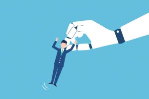 A robot hand lifts a worker in a suit up in the air